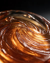 Close-up of amber pomade texture showing high-gloss finish